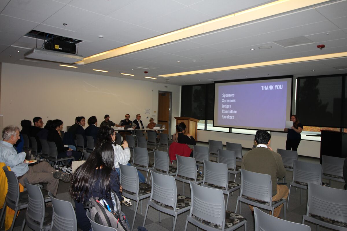 A wide view of the Diablo Room from the back as the closing thank-you slide — sponsors, screeners, judges, committee, speakers — fills the screen, with the judging table at the front of the room.